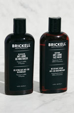 Brickell men's anti-aging moisturizer and face wash bottles on marble background