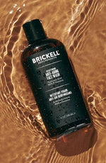Brickell Men's Products anti-aging face wash bottle on marble surface with shadow in the background.