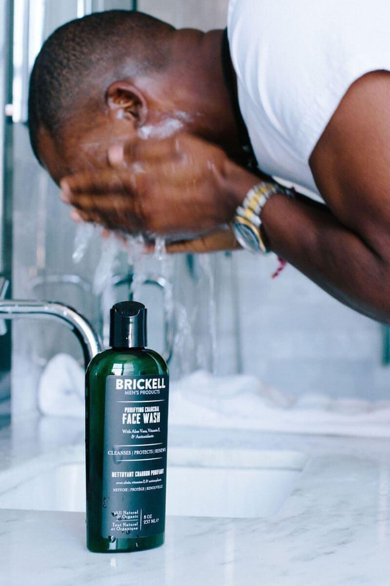 Man washing face in bathroom with Brickell Men's Daily Face Wash on counter